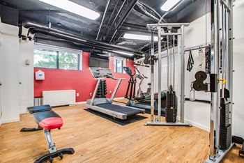 a gym with treadmills and weights in a home gym with wood flooring